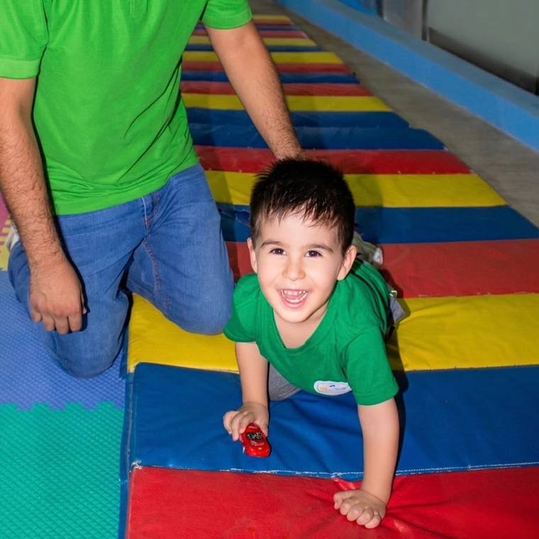 Niño de Baby Bloom sonriendo mientras juega sobre una colchoneta de colores