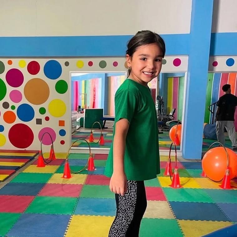 Niña de Baby Bloom sonriendo sobre una viga de equilibrio