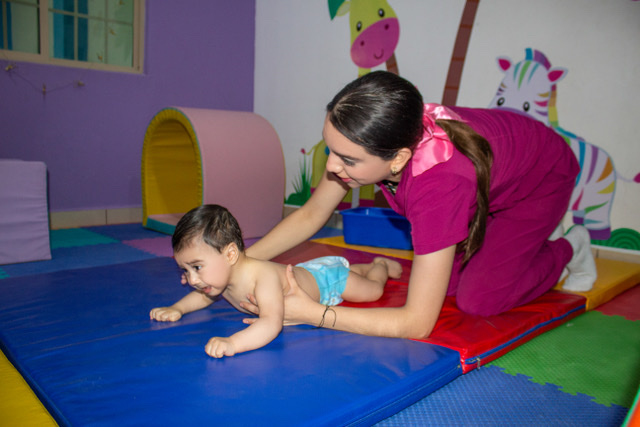 Especialista acompañando a una bebé durante una actividad de estimulación temprana en Baby Bloom